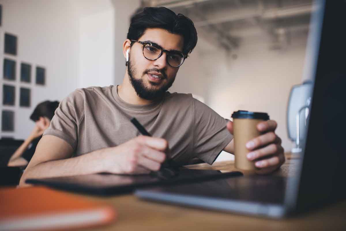 Focused man with coffee and laptop at Jawda Plus Institute.