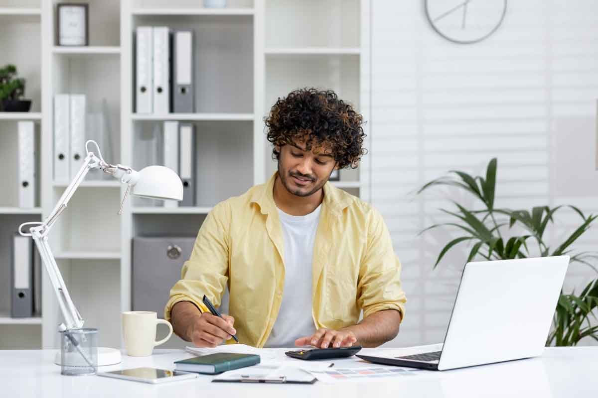 A young professional man with a laptop, books and coffee on his desk studying at Jawda Plus Institute.